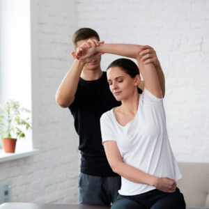 Ein junger Mann im schwarzen T-Shirt dehnt eine junge Frau mit weißem T-Shirt.