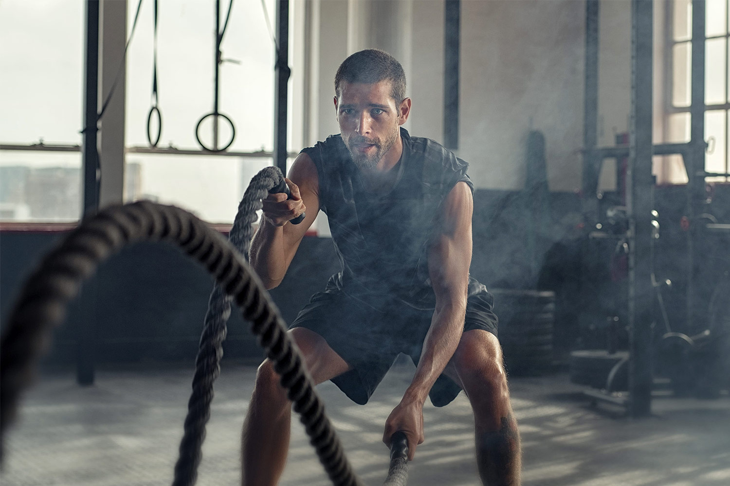 Mann trainiert mit Battle Ropes in Fitnessstudio für Kraftaufbau