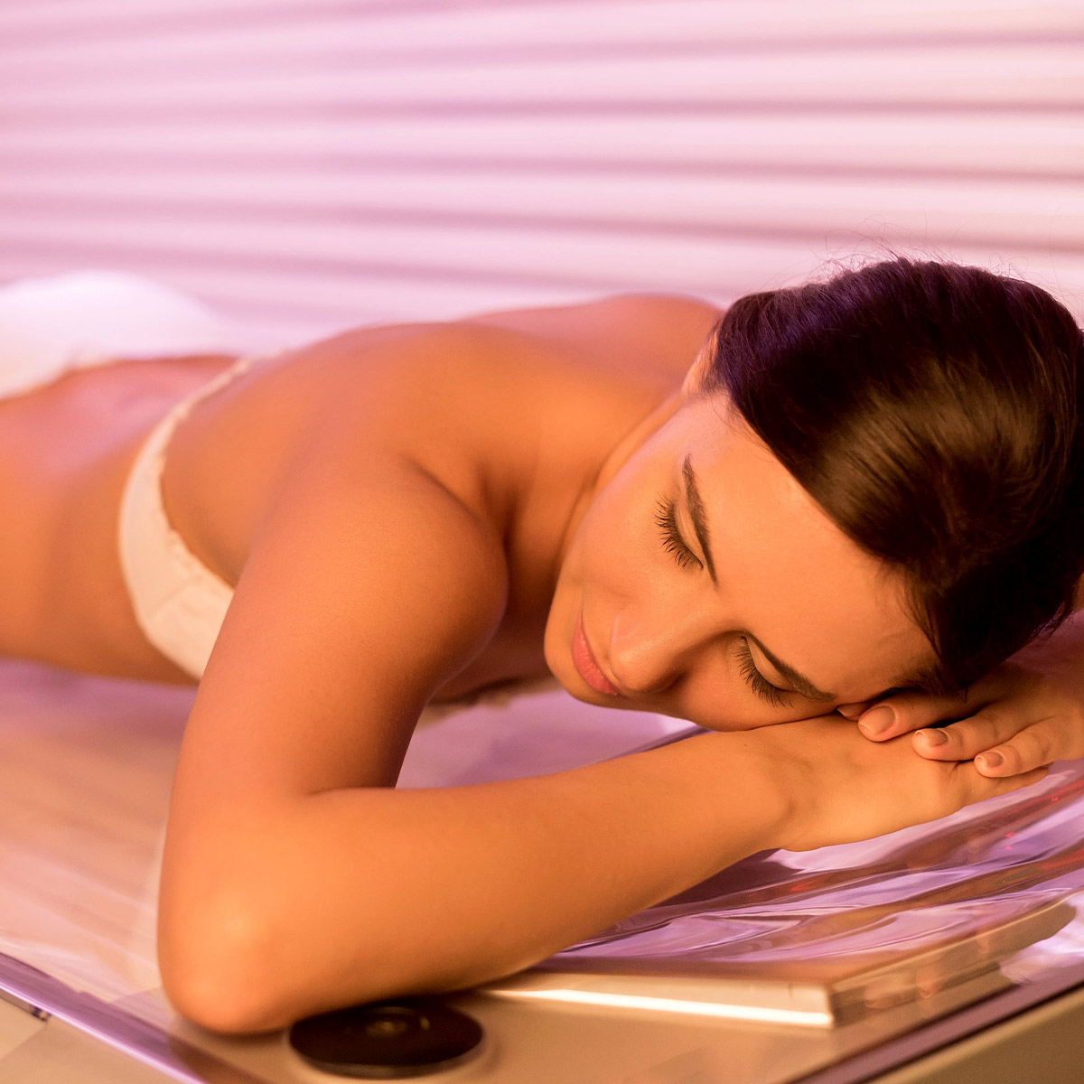 Person genießt ein Sonnenbad im Solarium mit einem Lächeln